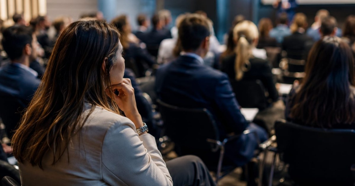 Panel de oradores en evento de innovación financiera con mayoría de mujeres en el público
