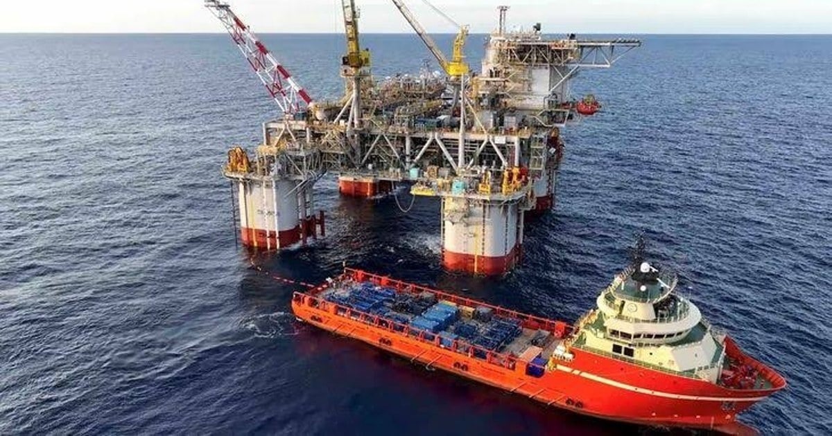 Torre de perforación petrolera en la meseta neuquina, con camiones y personal en el yacimiento