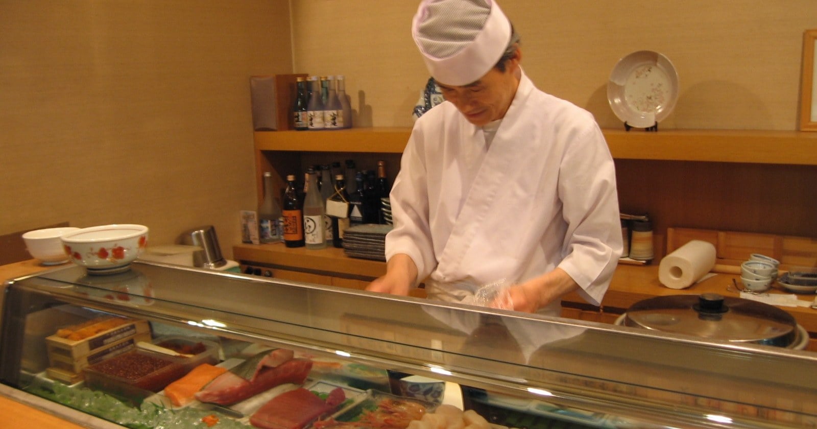 Primer plano de rolls de sushi servidos sobre una tabla de madera con palitos