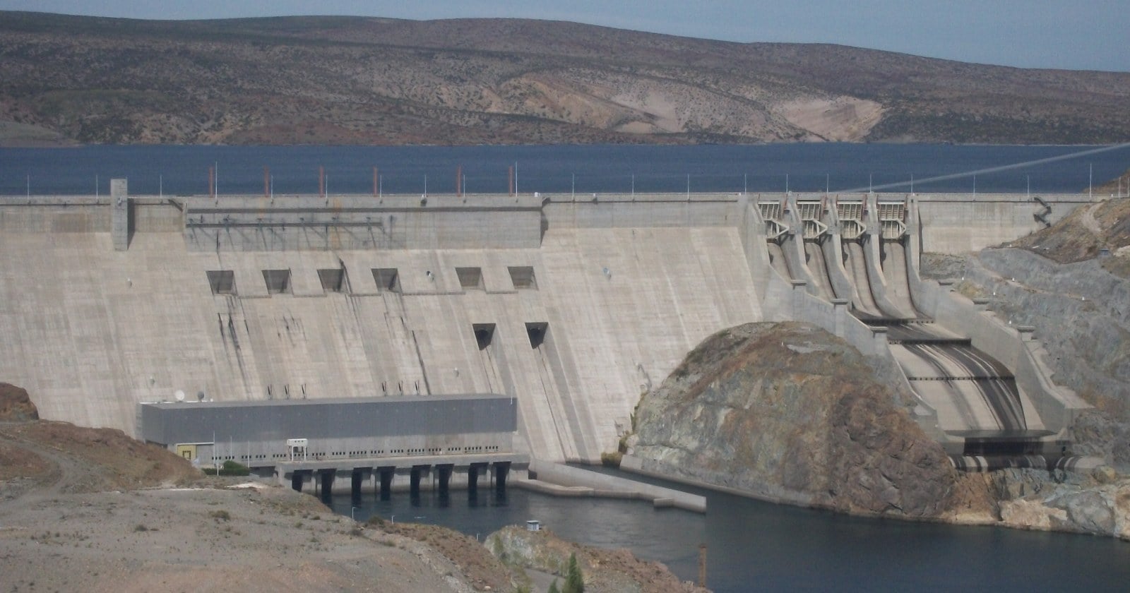 Presa de hormigón de Piedra del Águila sobre el río Limay, con el embalse detrás y la estepa alrededor